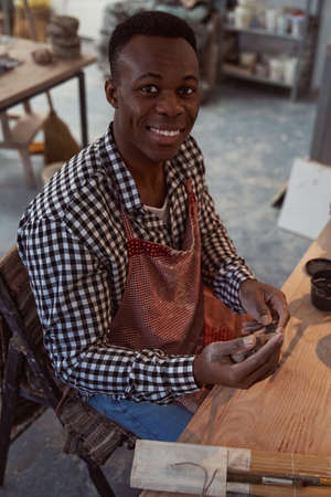 Joyous young male potter working with clay