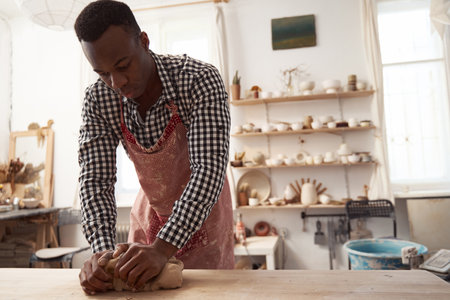 Experienced potter eliminating excess air bubbles during kneading processの写真素材