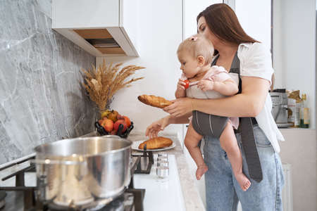 Beautiful elegant woman with kid is holding baking in hands at home apartmentの写真素材