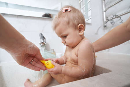 Charming baby girl washing in bathroom sink