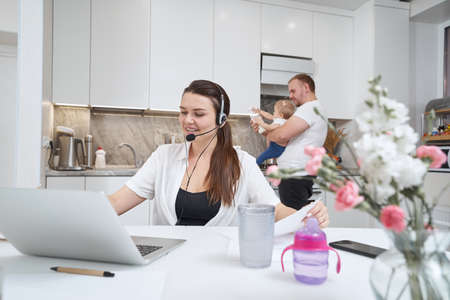 Woman working from home with laptop near her familyの写真素材