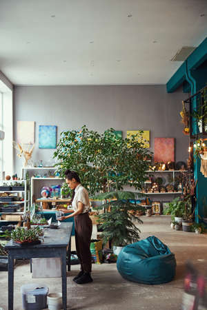 Concentrated florist adding soil to a florarium