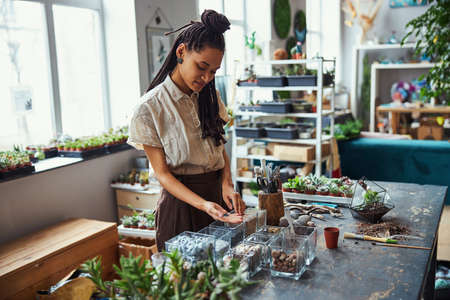 Concentrated floral designer choosing decorative items for a succulent terrarium