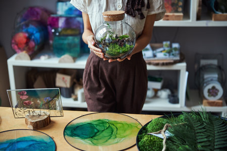 Female florist with a florarium standing at a tableの写真素材