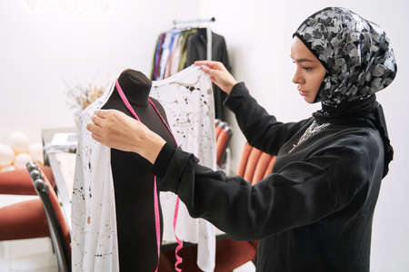 Young muslim woman is sewing traditional dress
