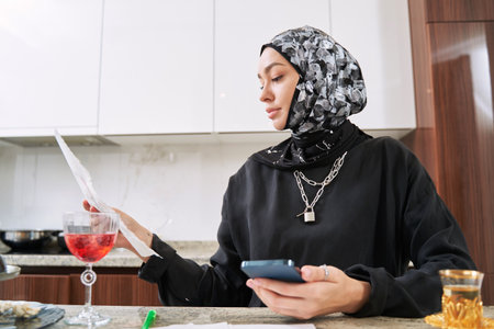 Young muslim woman with smartphone studyingat homeの写真素材