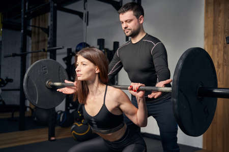 Woman having weight workout with make coach in gymの写真素材