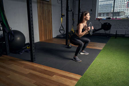 Woman doing exercise with fitness training disk in gym