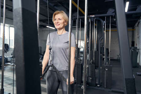Joyful woman using gym equipment during training