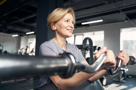 Smiling woman doing exercise with gym trainerの写真素材