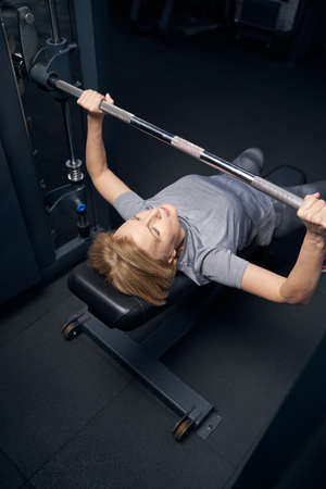 Woman using barbell press bench machine during workout