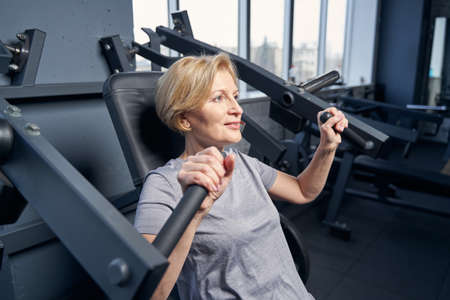 Woman using gym equipment in fitness clubの写真素材