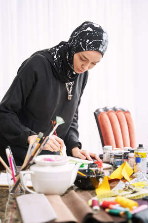 Woman in hijab making designes of traditional clothesの写真素材