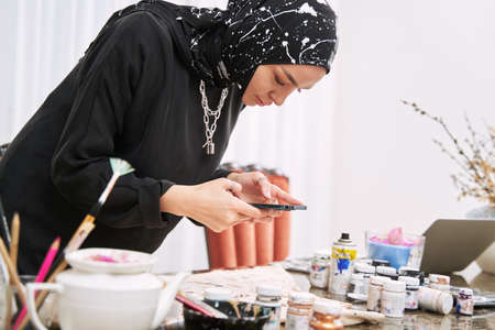 Muslim female designer picturing her handmade hijabs in workshop