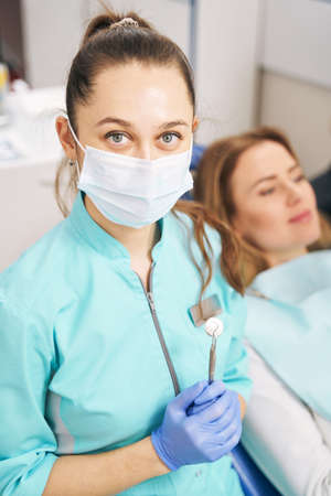 Female dentist with dental tools standing near patient in clinicの写真素材