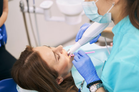 Dentist examining woman teeth with dental 3D scannerの写真素材