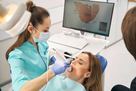 Dentist scanning woman teeth with dental intraoral 3D scannerの写真素材