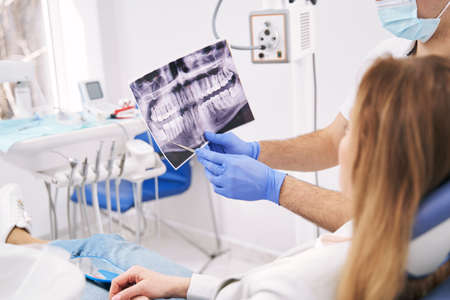 Doctor showing dental x-ray scan to woman in clinic