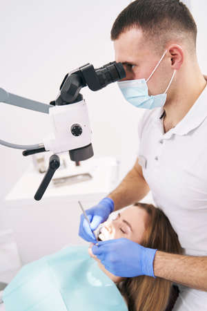 Dentist performing dental treatment with microscope in clinicの写真素材