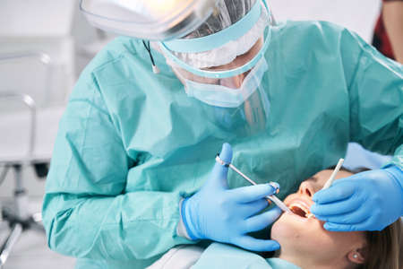 Male dentist performing dental procedure in stomatology clinicの写真素材