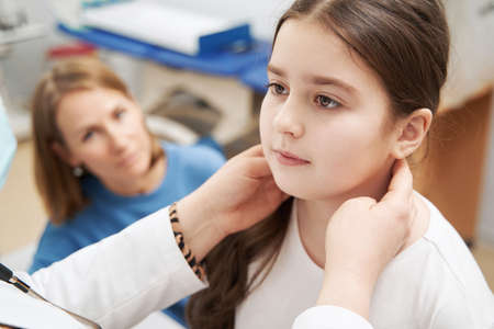 Female doctor examining child lymph nodes in clinicの写真素材