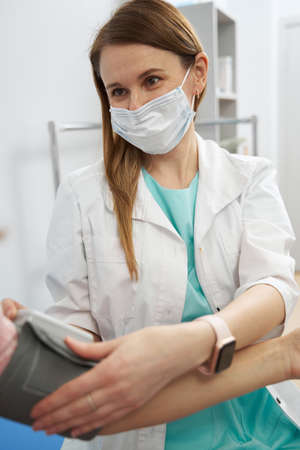 Female doctor checking patient blood pressure in clinic