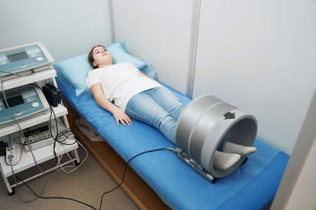 Girl receiving magnetotherapy treatment in modern clinicの写真素材