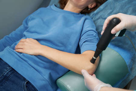 Female patient receiving shockwave therapy in clinic