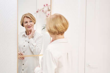 Tender senior female person touching her skinの写真素材