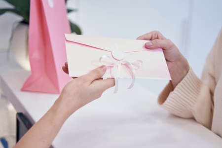 Aesthetic clinic employee presenting discount voucher to clientの写真素材