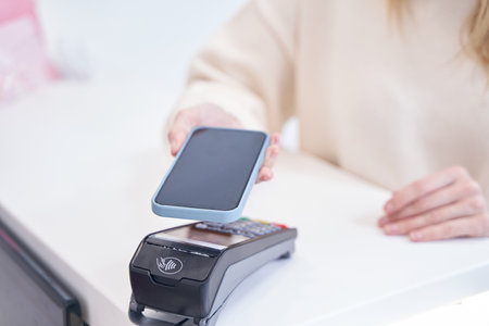 Beauty clinic client making contactless payment at reception deskの写真素材