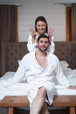 Happy wife giving bunny ears to husband in bedの写真素材