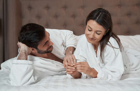 Couple relaxing in bed of their hotel suiteの写真素材