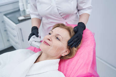 Woman having face lifting procedure in cosmetology clinic