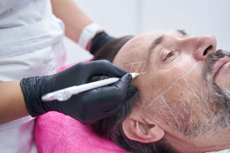 Focused photo on female hand holding white markerの写真素材