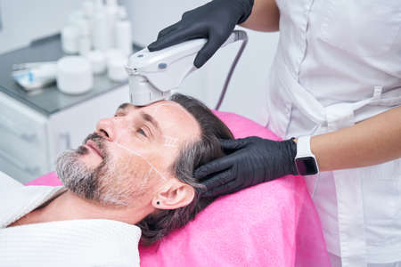 Professional cosmetologist doing skincare procedure for patientの写真素材