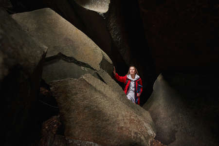 Female looking at light coming through hole in empty cave