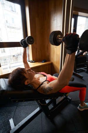 Professional sportswoman performing upper chest exercise at gym