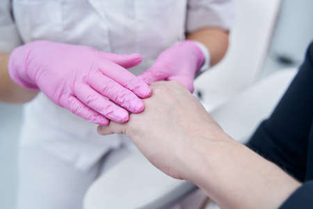 Close up photo of cosmetologist and client hands before rejuvenation treatment
