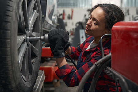 Female auto mechanic repairing car wheel at service station