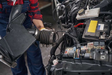 Woman automobile mechanic repairing car engine in garage