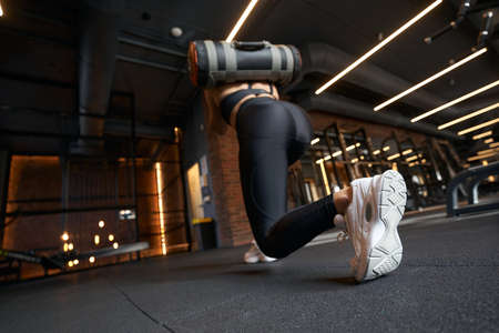 Female athlete doing lunge during gym workoutの写真素材