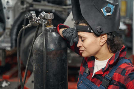 Woman auto mechanic standing near gas cylinder in garage