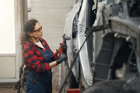 Female auto mechanic repairing car in auto service garage
