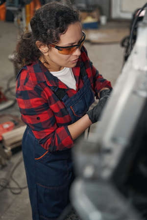Woman auto mechanic working at car repair service station