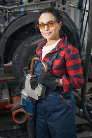 Woman car mechanic using auto repair equipment in garageの写真素材