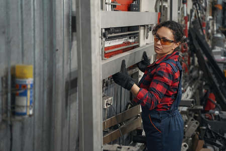Woman car mechanic working at auto repair station