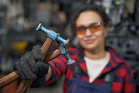 Female auto mechanic hand holding car repair hammersの写真素材