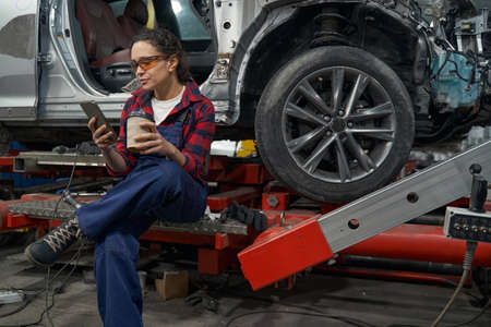 Female auto mechanic using smartphone in car garageの写真素材