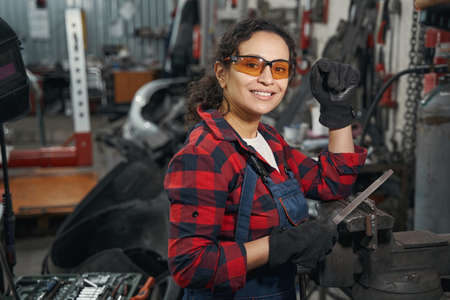 Cheerful woman auto mechanic working in car repair shop